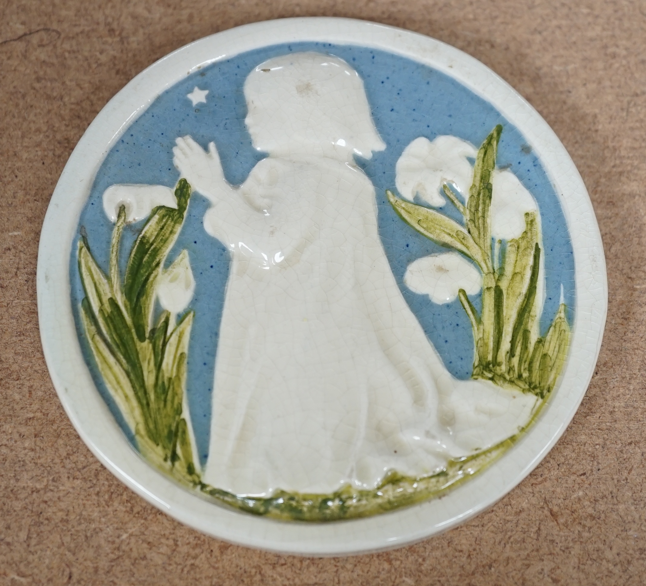 A small Della Robbia circular ceramic wall plaque of a child praying, signed to the base, 10.5cm in diameter. Condition - fair to good